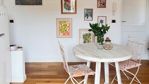 Een eetruimte met een ronde tafel, vier stoelen, een hanglamp en enkele ingelijste foto's aan de muur.