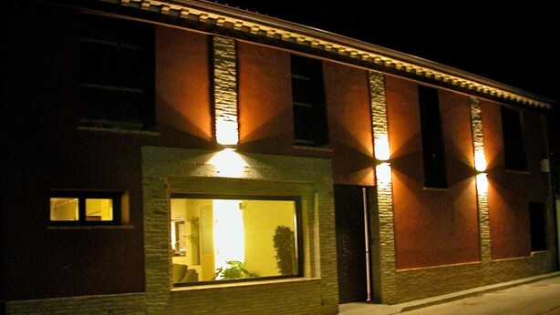 A building with a large window and a door, illuminated by exterior lighting.