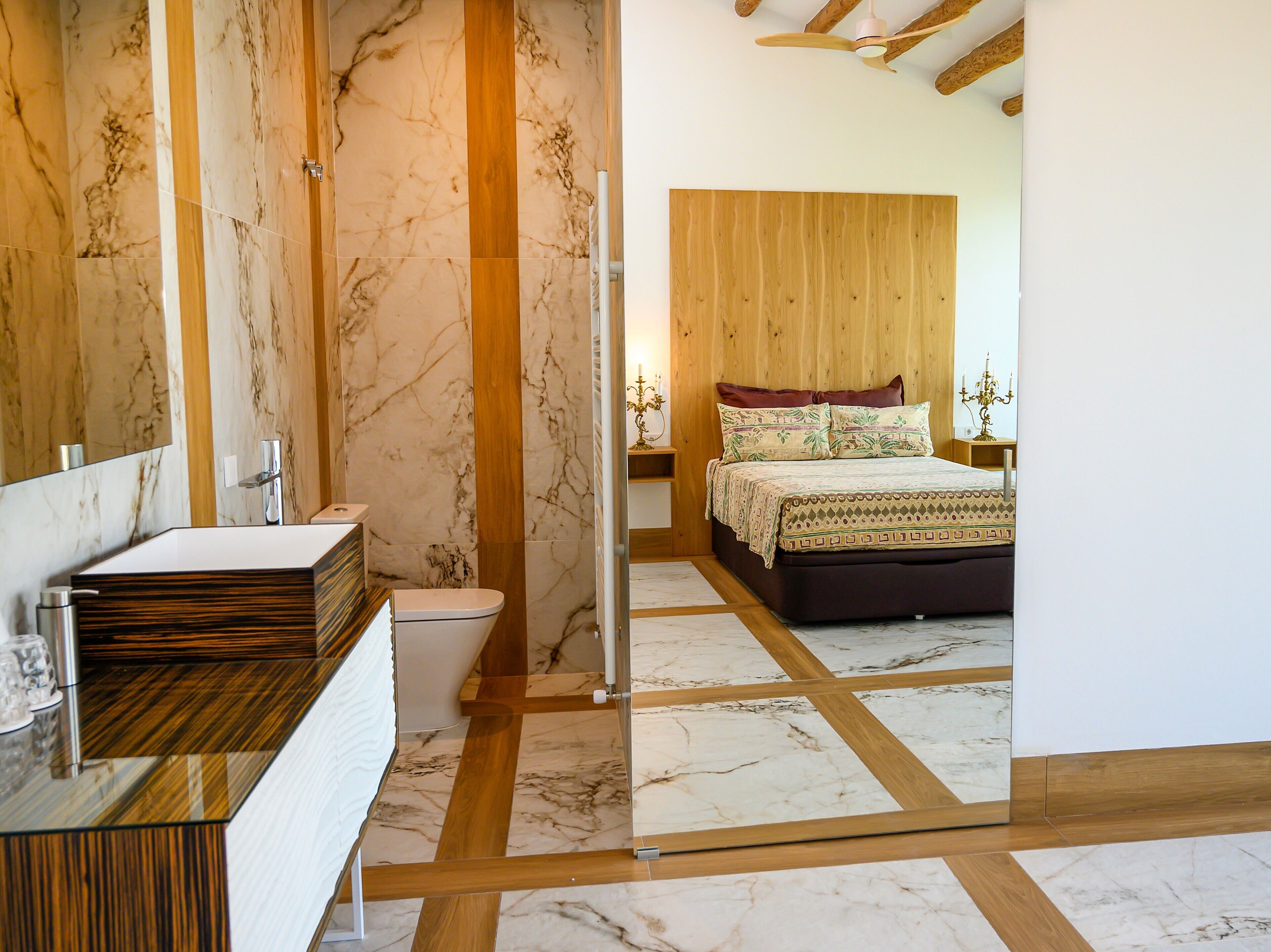 Une salle de bain moderne avec un meuble-lavabo en marbre, des toilettes et un espace douche.