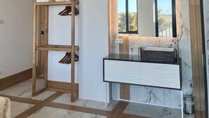 A bathroom with a marble vanity, wooden beams, a hanging towel rack, and a window with a view.
