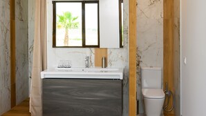 Un baño moderno con tocador de mármol, inodoro y zona de ducha.
