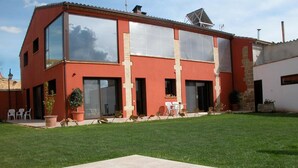 Una casa moderna de dos pisos con piscina, ventanas amplias y un jardín bien cuidado.