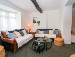 A living room with two leather sofas, a round coffee table, and a lamp. - Broad Beams (Neston)