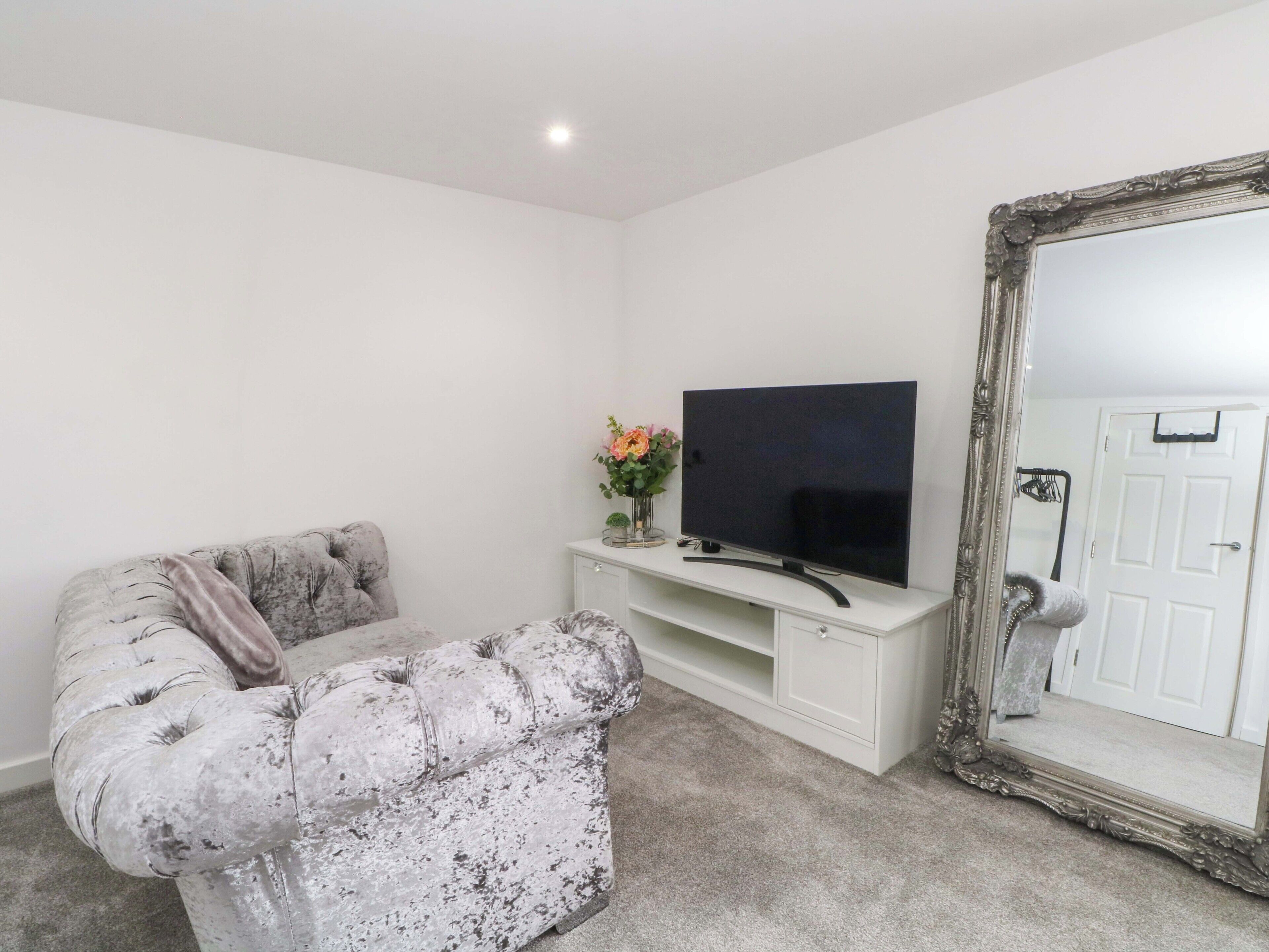 A living room with a sofa, a flat-screen TV, a cabinet, and a large mirror.
