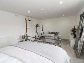 Ein Schlafzimmer mit einem Bett, einem Sessel, einem Schreibtisch, einem Spiegel und einer Heizung.
