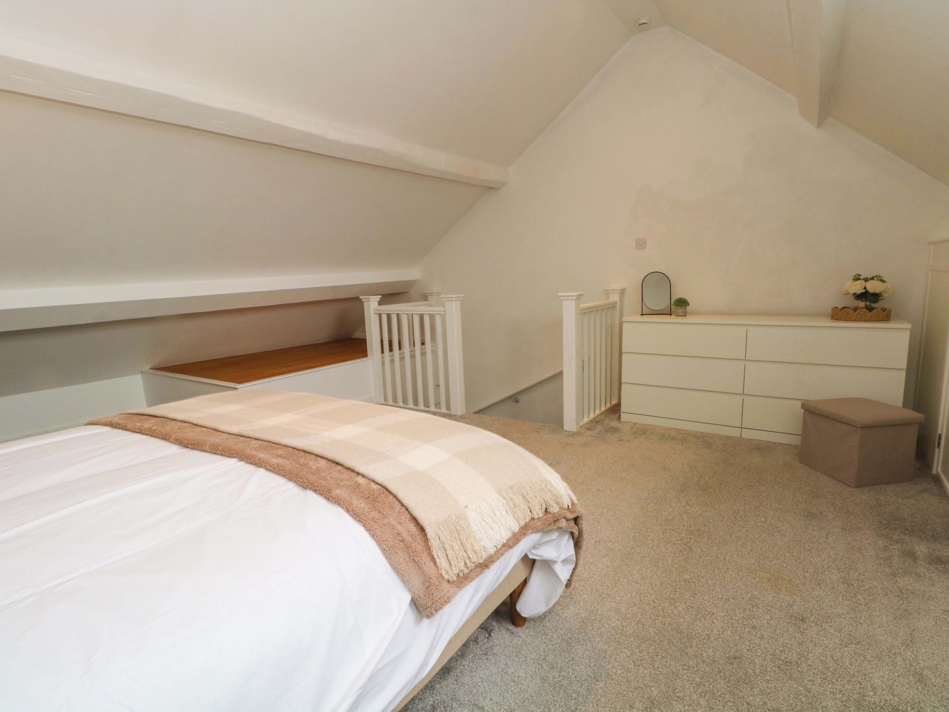 A bedroom with a bed, a dresser, a small stool, and a white radiator.
