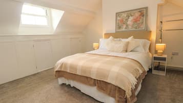 A bedroom with a bed, two bedside tables, a nightstand, a window, and a painting on the wall.