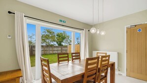 A dining area with a table and chairs, a view of the outdoors, and a door with a sign.