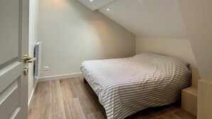 Een slaapkamer met dakraam, een bed, nachtkastje en radiator.