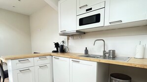 Een moderne keuken met witte kasten, een roestvrijstalen spoelbak en een houten aanrecht.