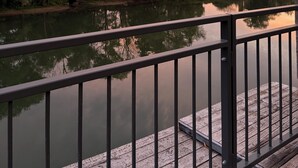 Een rustige rivier met een houten steiger en een metalen hek.