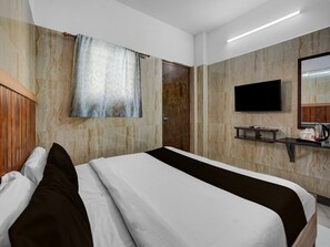 Ein Hotelzimmer mit Bett, Wand-Fernseher, kleinem Tisch mit Wasserkocher und Holz-Kopfseitenverkleidung.