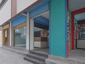 Ein Gebäude mit blau abgesetztem Eingang, einer Treppe zu einer Tür und einer Wand mit farbenfrohen Plakaten.