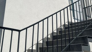 A staircase with a metal railing leading to a door, against a white wall under a clear blue sky. - Beautiful vacation rental 200 meters from Lake Balaton for up to 4 people, with a balcony (Siófok)