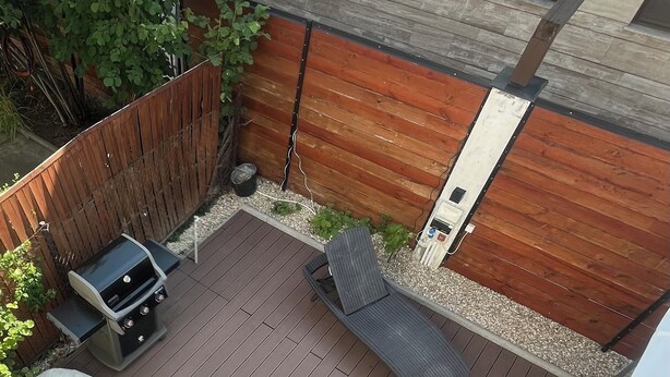 A wooden deck with a grill, two lounge chairs, a small round table, and a white umbrella. - Beautiful vacation rental 200 meters from Lake Balaton for up to 4 people, with a balcony (Siófok)