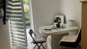 A dining area with a table, chairs, a potted plant, and a toaster. - Beautiful vacation rental 200 meters from Lake Balaton for up to 4 people, with a balcony (Siófok)