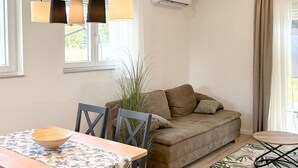 En stue med sofa, spisebord med stole, en plante og en loftlampe.