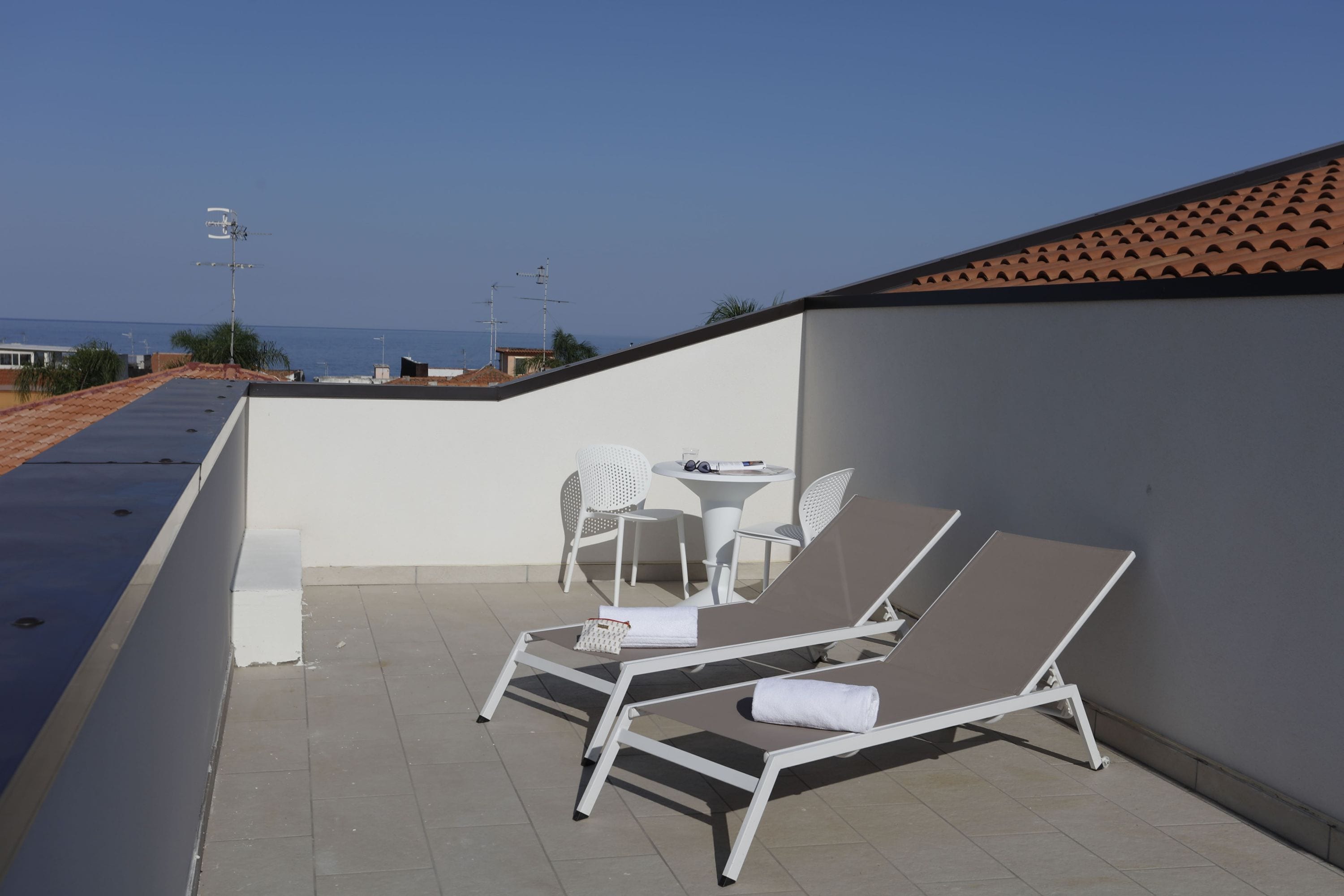Una terrazza sul tetto con due lettini, un tavolino e due sedie.