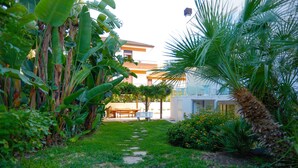 Un sendero en un jardín que lleva a un edificio con una banca y una mesa.