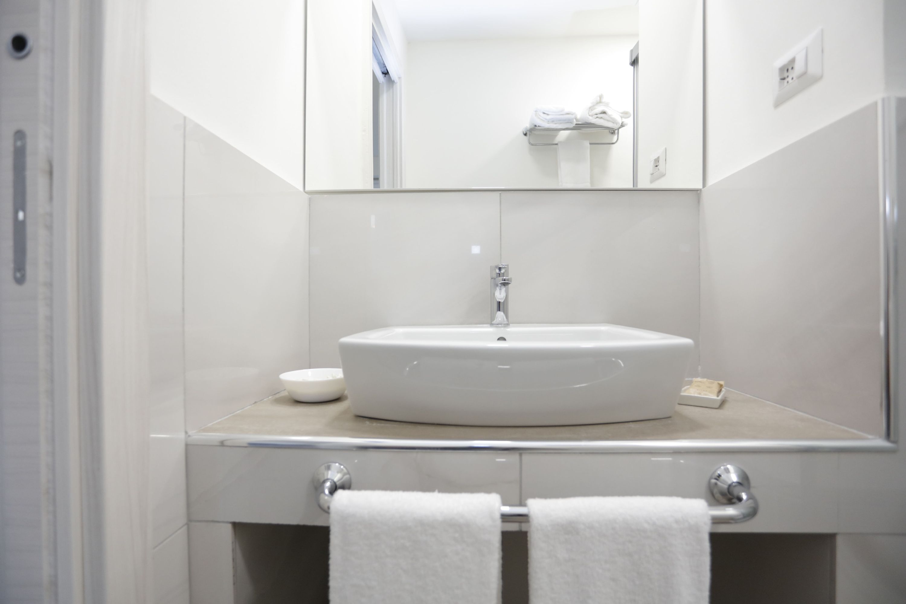 Une salle de bain avec un lavabo blanc, un miroir et un porte-serviettes.