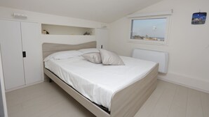 Ein Schlafzimmer mit einem Bett, einem Fenster mit Blick, einem Heizkörper und einem Kleiderschrank.