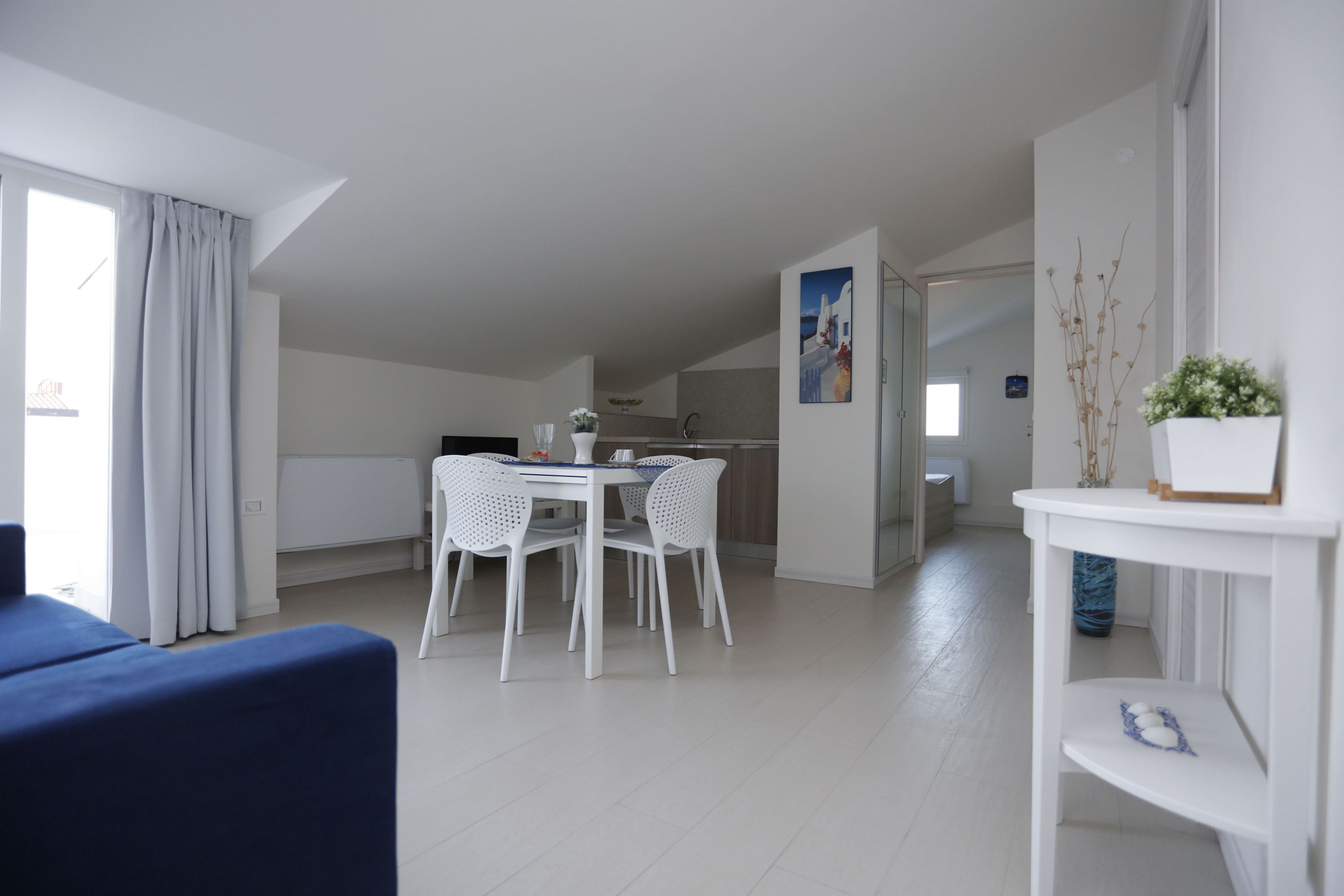 Una stanza moderna e luminosa, con un tavolo da pranzo e sedie, un divano e un piccolo tavolino con oggetti decorativi.