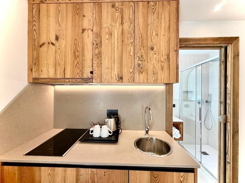 Eine moderne Küche mit Holzschränken, einer Edelstahlspüle und einer schwarzen Induktionskochplatte.