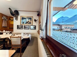 Un comedor con vista a las montañas, muebles de madera y cuadros en la pared.