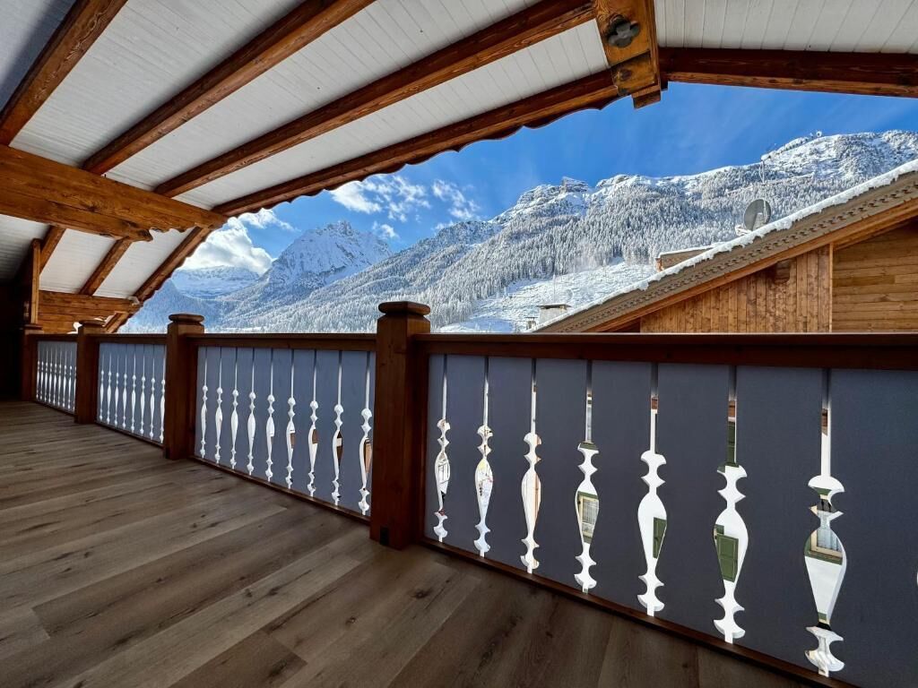 Un balcón de madera con vista a montañas nevadas.