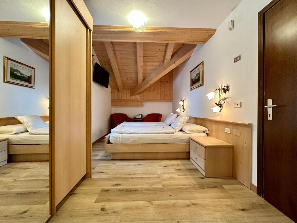 A bedroom with a wooden ceiling, a bed, bedside tables, and wall-mounted lights.