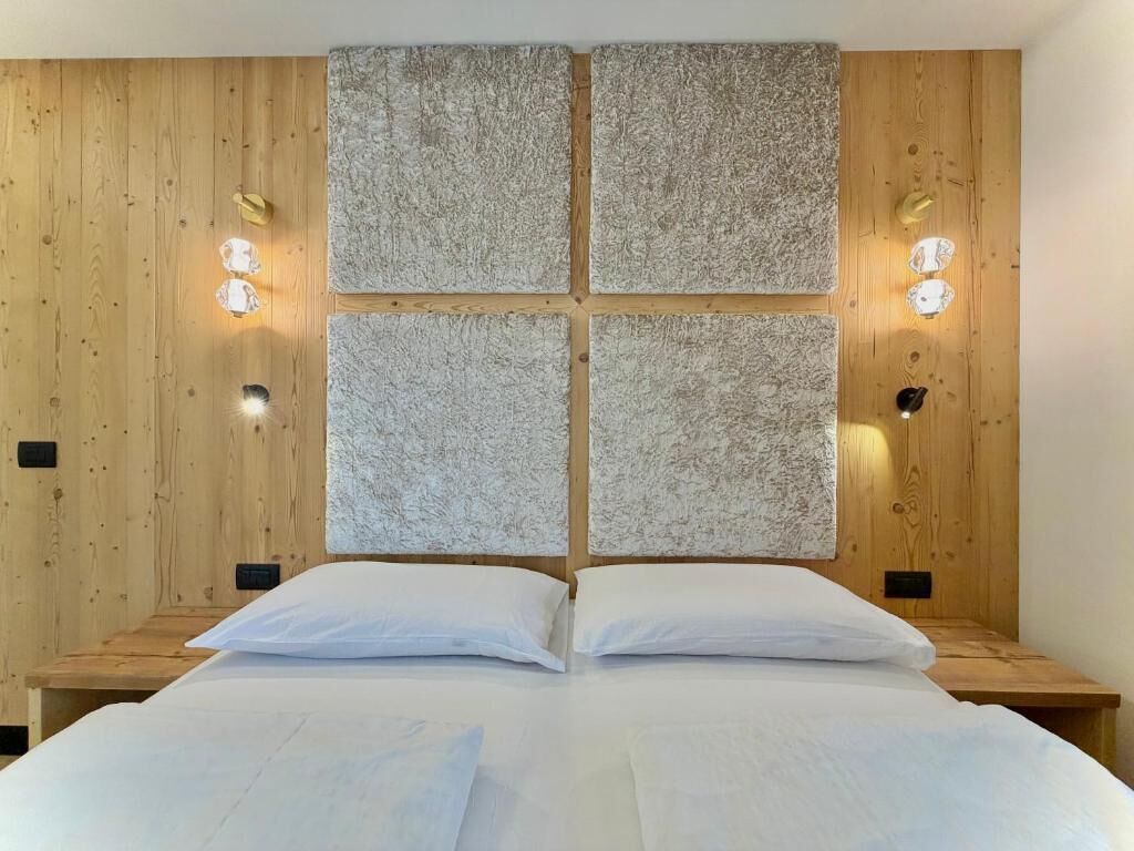 Een kamer met een houten hoofdbord, twee nachtkastjes en een bed met witte lakens.