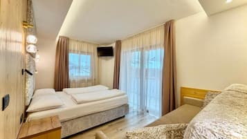 Ein Hotelzimmer mit Bett, Nachttisch aus Holz, Fernseher und einem Fenster mit Vorhängen.