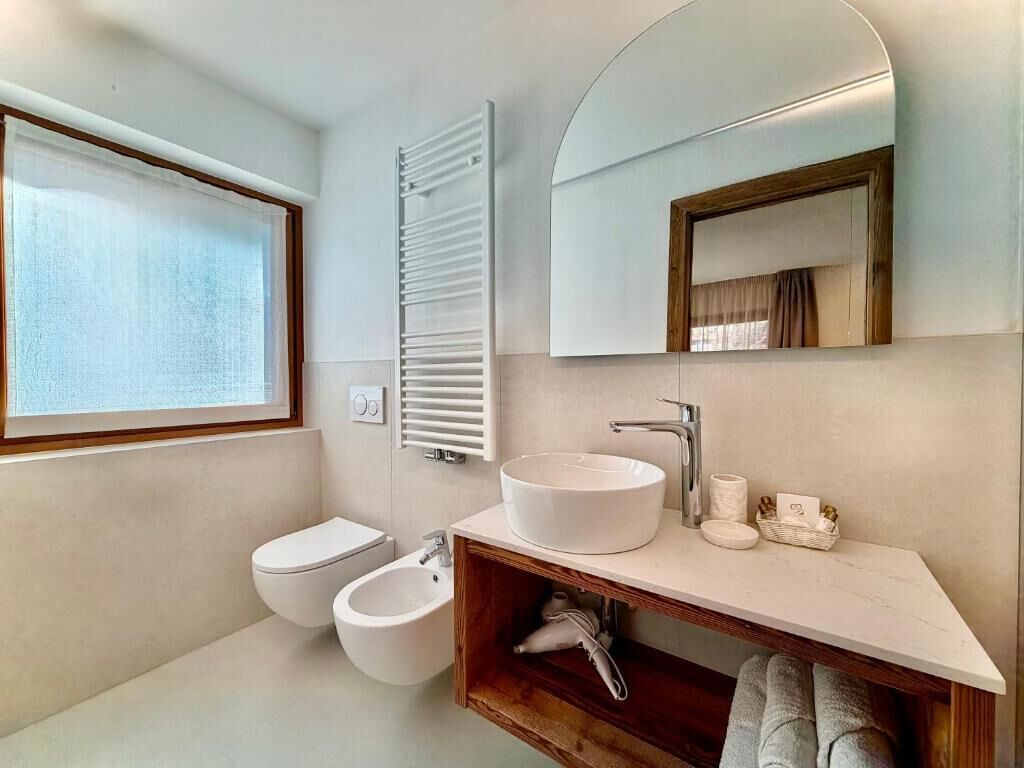 Un baño moderno con lavamanos blanco, un espejo y un inodoro.