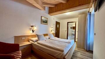 Une chambre à coucher avec un lit en bois, des lampes de chevet, une table de chevet, une chaise et une porte donnant sur une salle de bain.
