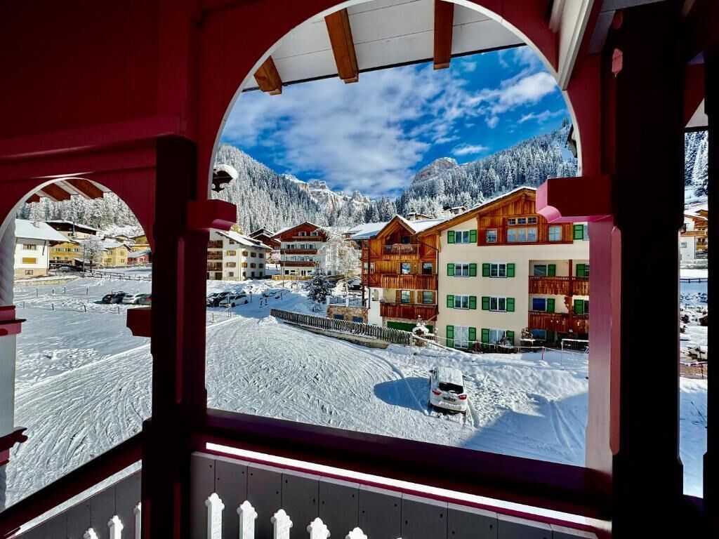 Un villaggio montano innevato con case di legno e cielo sereno.