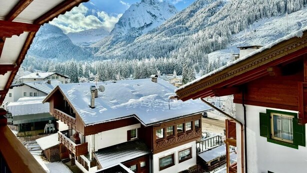 A mountain village with snow-covered buildings and a view of snow-capped mountains.