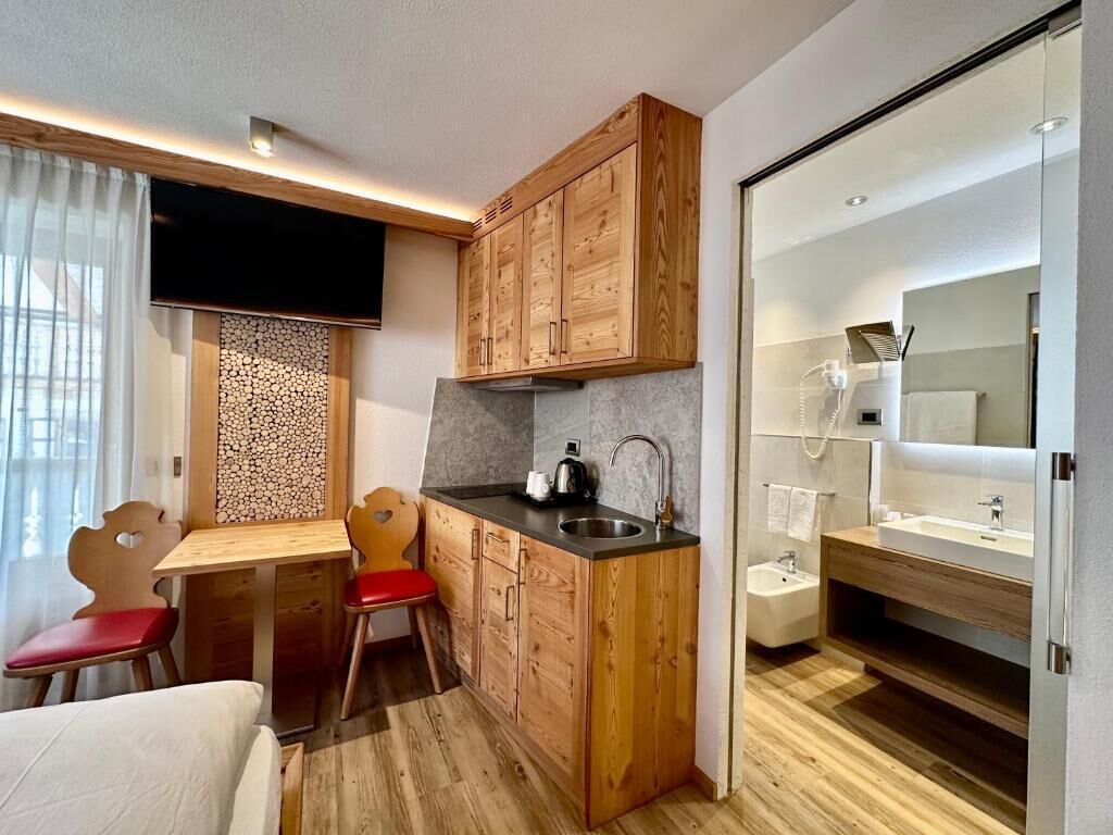 Una cocina compacta con armarios de madera, un lavamanos y un pequeño comedor con sillas.