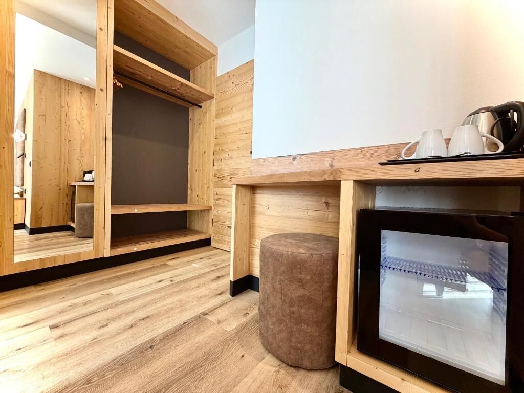 A wooden interior with a sofa, a small ottoman, a coffee table, and a television.