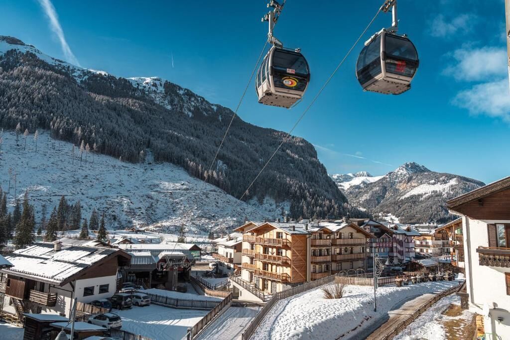 A ski resort with a cable car system, wooden buildings, and snow-covered mountains.