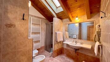 A bathroom with a skylight, a shower, a sink, and a toilet.