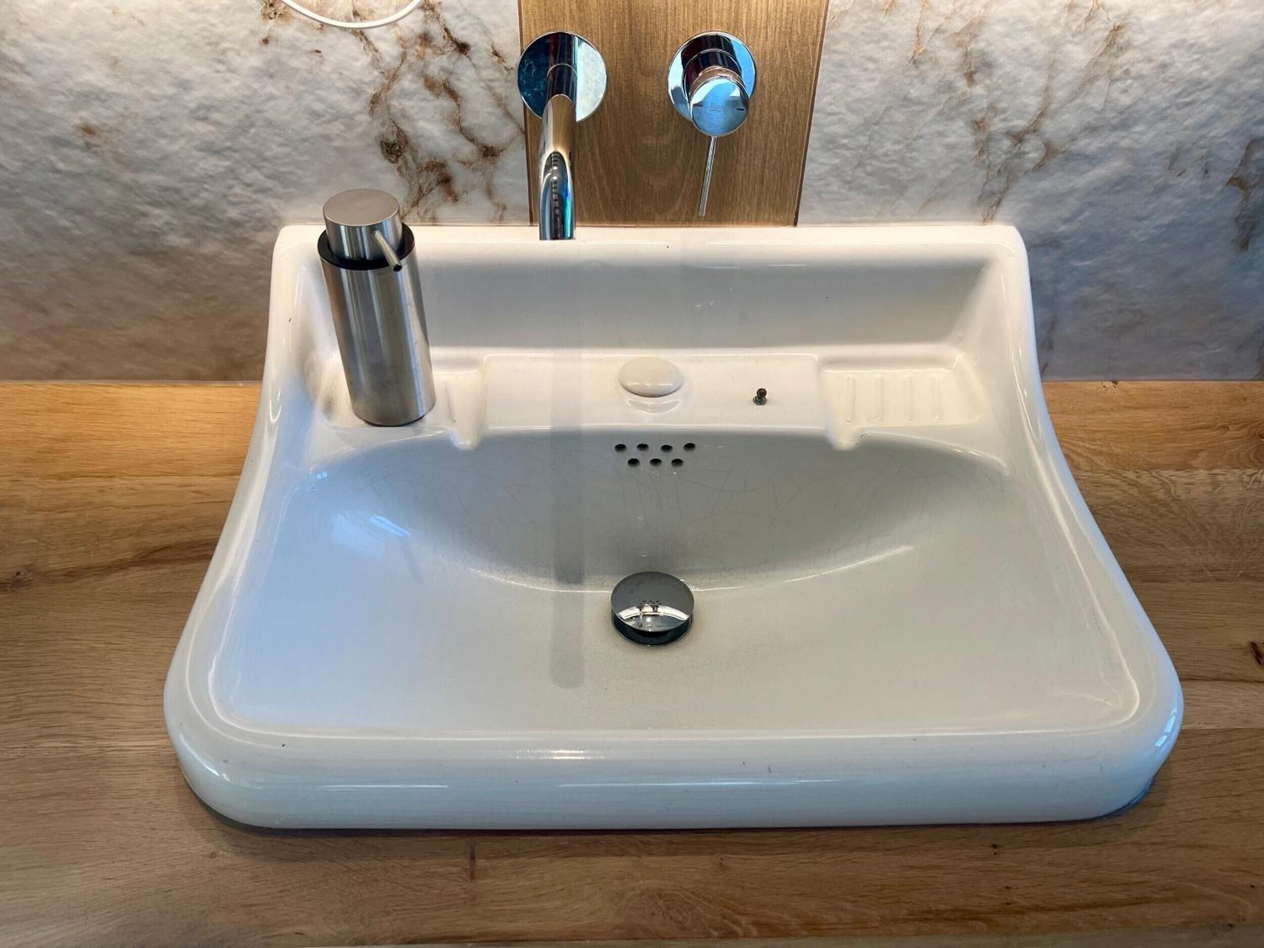 A white sink with a single faucet and a drain stopper.