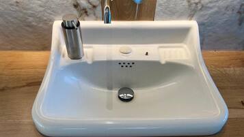 A white sink with a single faucet and a drain stopper.