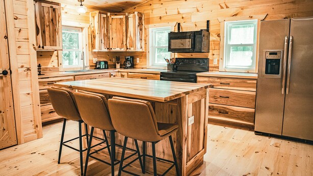 Una cucina in stile baita con isola centrale, sgabelli da bar, frigorifero e forno a microonde.