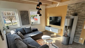 A modern living room with a sectional sofa, a flat-screen TV, a fireplace, and a stone accent wall.