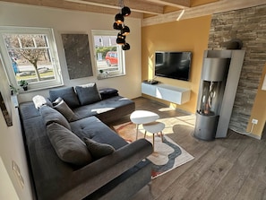 A modern living room with a sectional sofa, a flat-screen TV, a fireplace, and a stone accent wall.