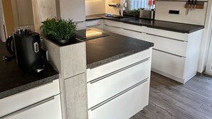 Eine moderne Küche mit weißen Schränken, einer zentralen Kochinsel und einer Holzbalkendecke.