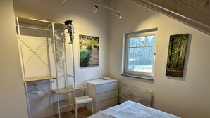Ein Schlafzimmer mit einem Bett, einem Fenster, einer Heizung und Bildern an den Wänden.