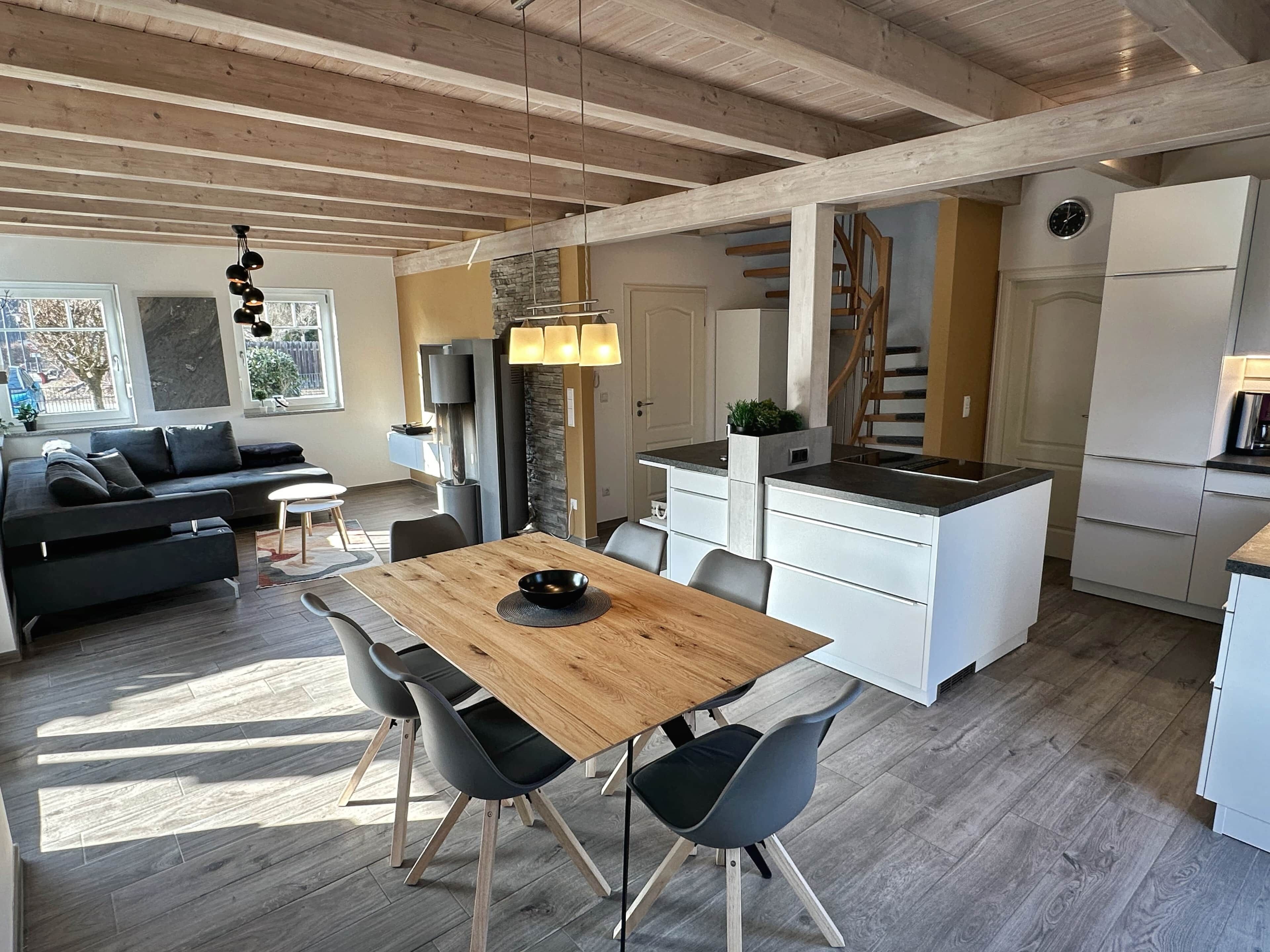 A modern kitchen with white cabinets, a wooden dining table, and a built-in island.