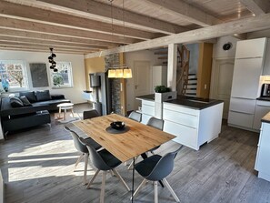 A modern kitchen with white cabinets, a wooden dining table, and a built-in island.