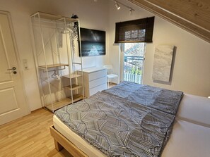 Een slaapkamer met een bed, een kledingkast, een bureau en een raam met uitzicht.